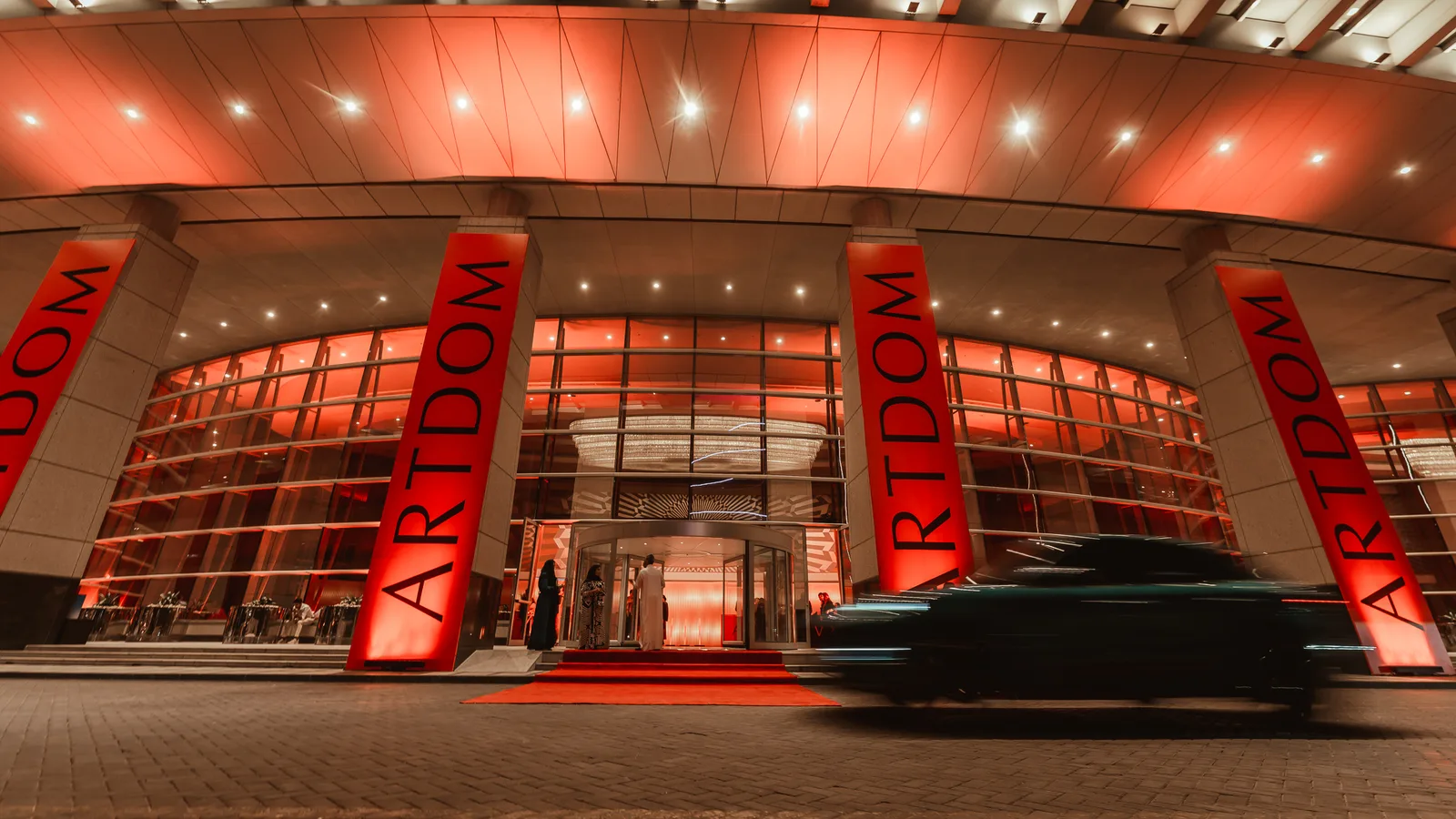 The entrance to ARTDOM Riyadh, with tall ARTDOM banners lit in red